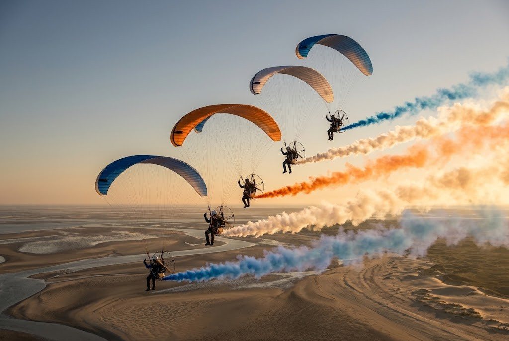A formation of paramotors trailing coloured smoke