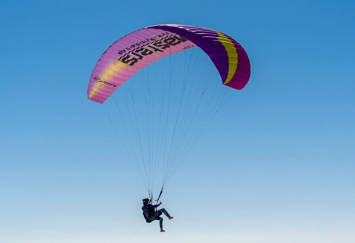A magenta wing soaring over the dunes